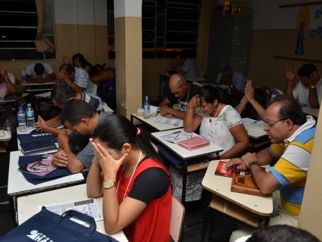 Participantes em oração, clamando a Deus, durante a última aula do sábado à noite.